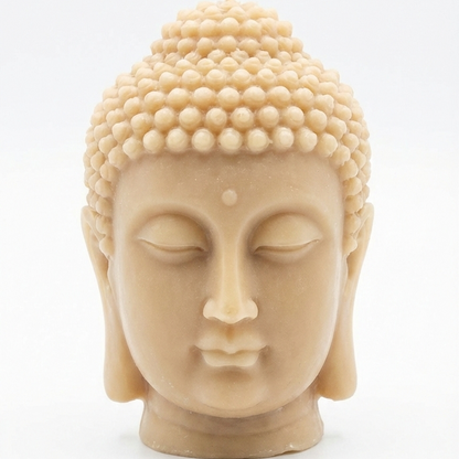 Vela de soja artesanal con forma de cabeza de Buda en tono arena natural sobre fondo blanco minimalista.