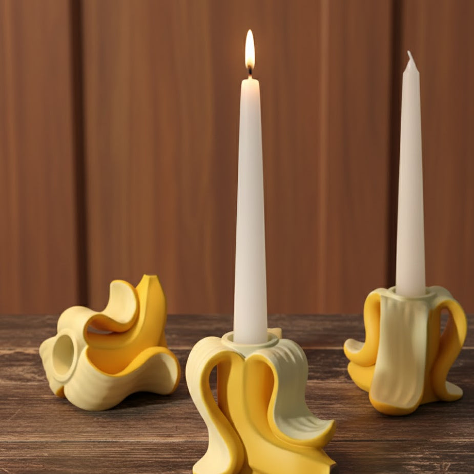 Portavelas de plátano en resina acrílica amarilla sobre mesa de madera oscura con velas de soja encendidas, creando un ritual de bienestar en casa y calidez.